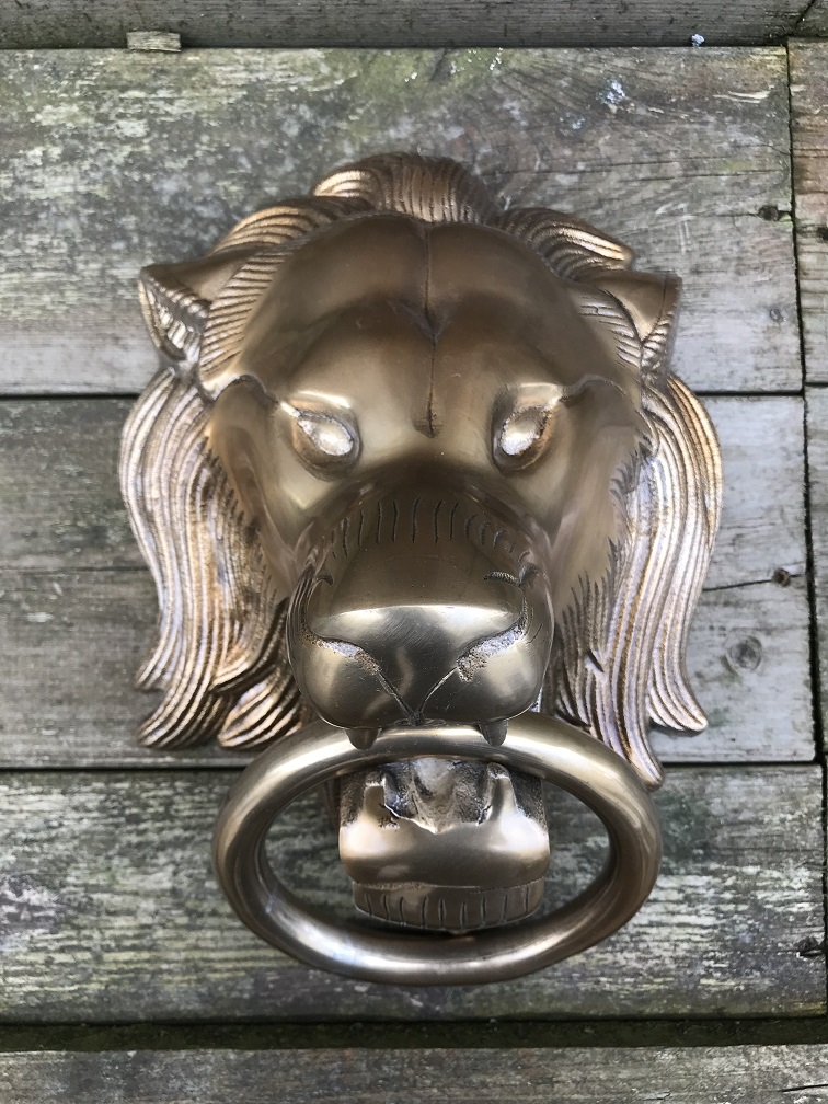 Een leeuwenkop, gemaakt van aluminium in messing kleur, als deurklopper