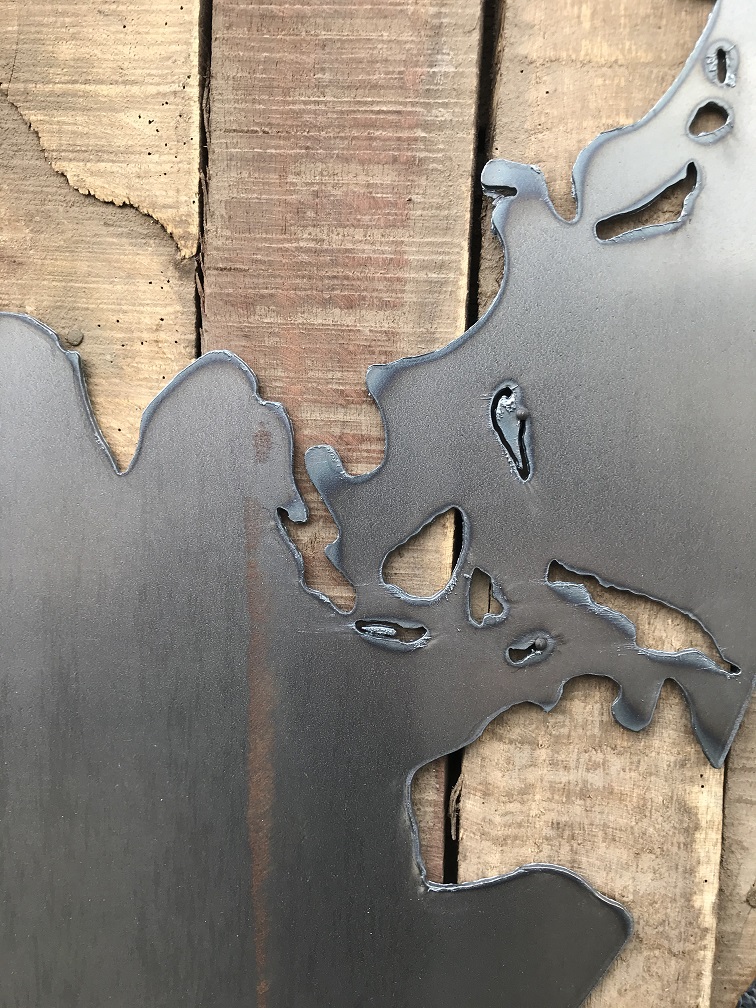 Ein großes Wandornament aus Holz mit einer Welt darauf, ein Meer aus Metall