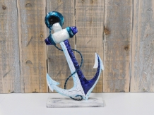 Beautiful decorative metal anchor on wooden stand.