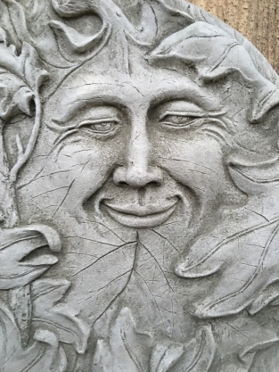 Wall ornament stone round, with an image of the cheerful oak leaf man, forest spirit.