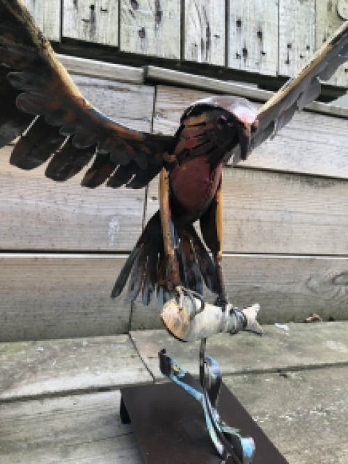 Een metalen kunstwerk van een adelaar die een vis vangt, ''IRON EAGLE''