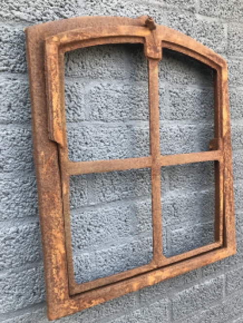 An antique-looking stable window, foldable open, untreated cast iron, resting surface, window