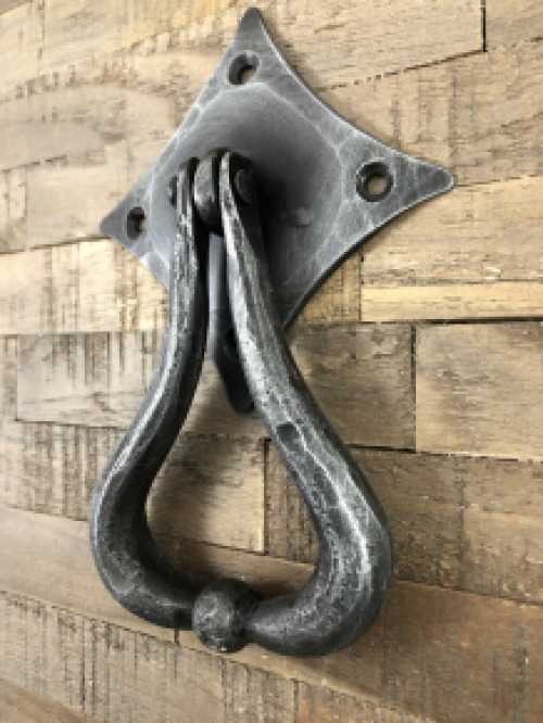 Beautiful design is this door knocker wrought iron for on the rustic wooden door.