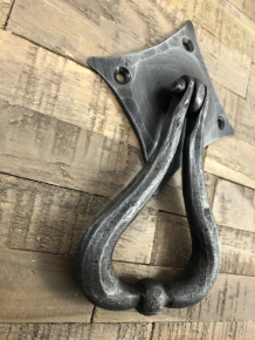 Beautiful design is this door knocker wrought iron for on the rustic wooden door.