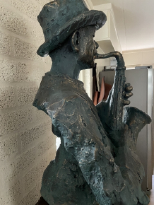 Beautiful torso of a jazz musician with saxophone in green-gold