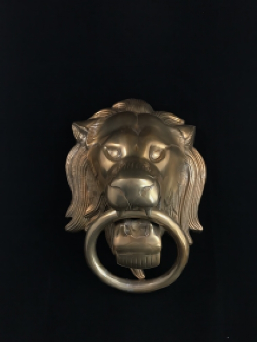 A lion's head, made of aluminum in a brass color, as a door knocker