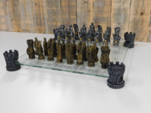 A chess game with the theme: ''knight-dragons'', beautiful chess pieces like medieval knights on glass chessboard with rooks.