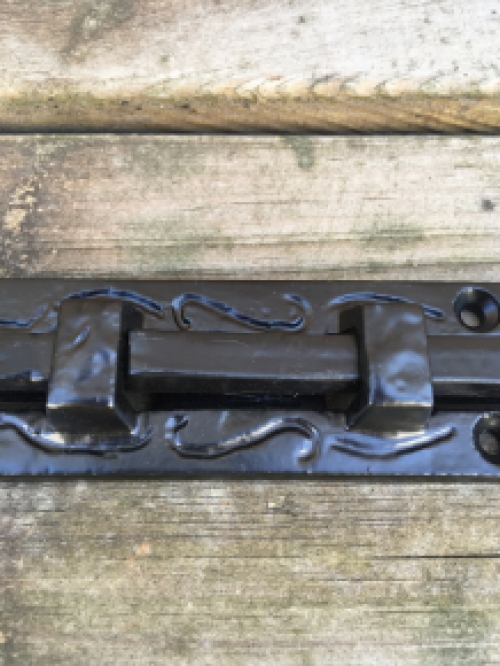 Een fraaie deurgrendel, mat zwart, gemaakt van smeedijzer