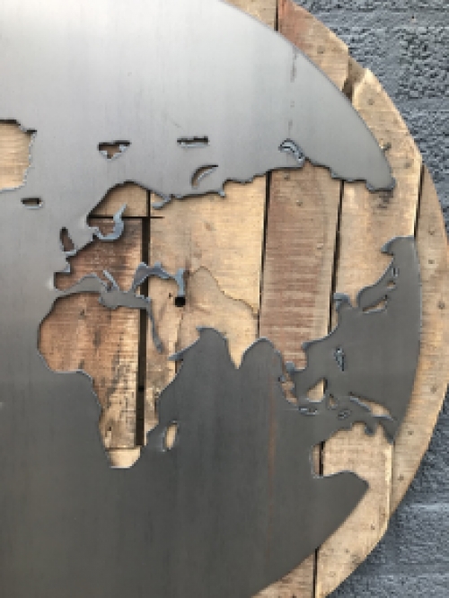 Ein großes Wandornament aus Holz mit einer Welt darauf, ein Meer aus Metall